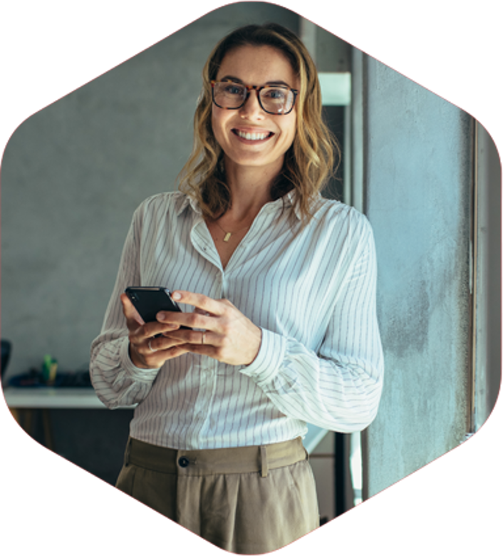 A woman happily holds a smartphone, radiating joy as she looks at the screen, capturing a moment of connection and technology.